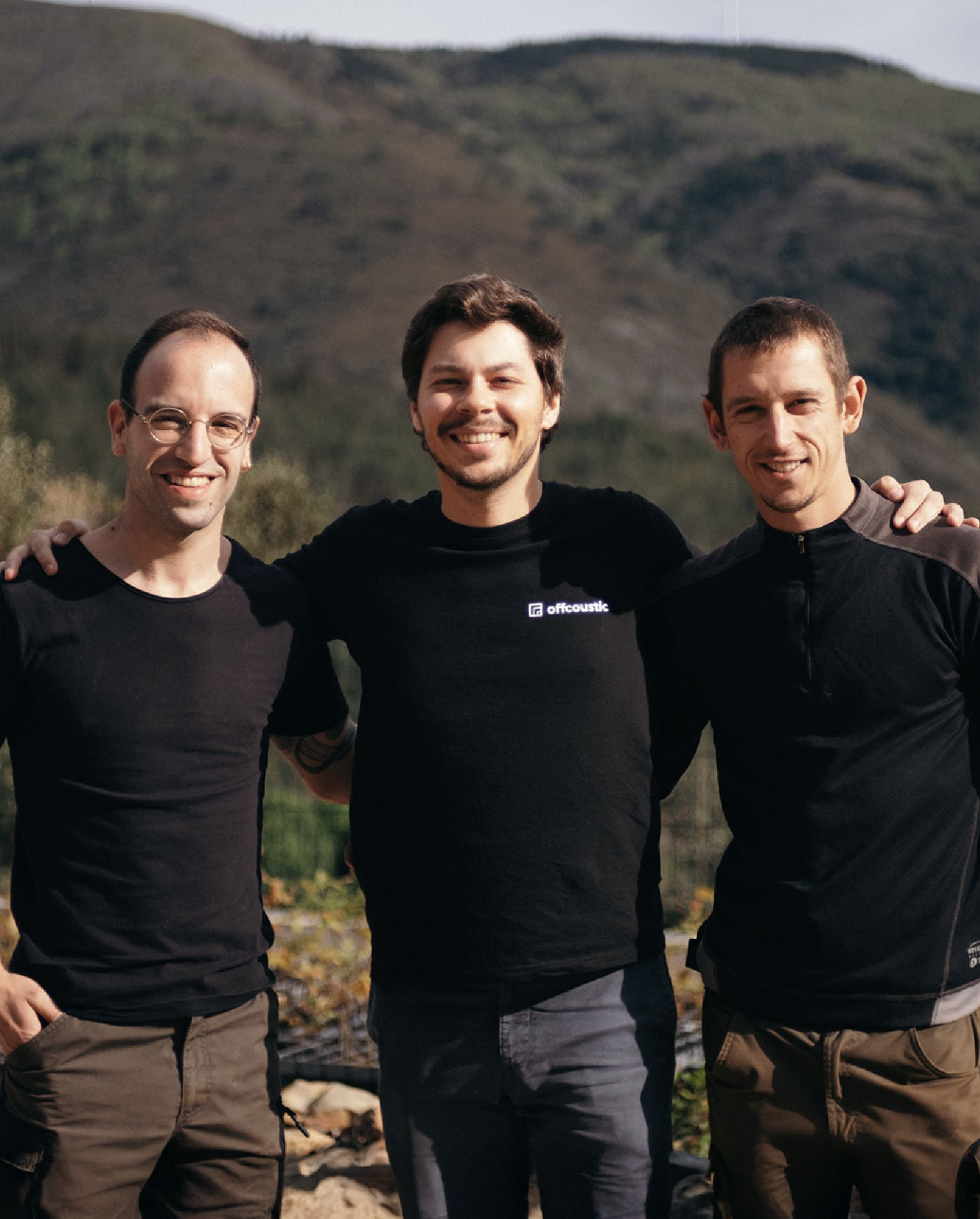 Three team members smiling against beautiful mountain landscape